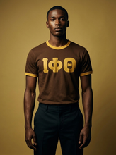 Load image into Gallery viewer, Man wearing a brown shirt with gold lettering against a beige background