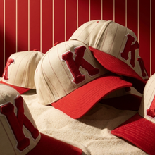 Load image into Gallery viewer, Beige and red baseball caps with a letter 'K' on a red background