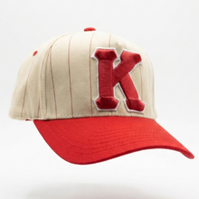 Load image into Gallery viewer, Beige and red cap with a large 'K' on a white background

