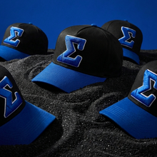 Load image into Gallery viewer, Black caps with blue symbols on a dark surface and blue background
